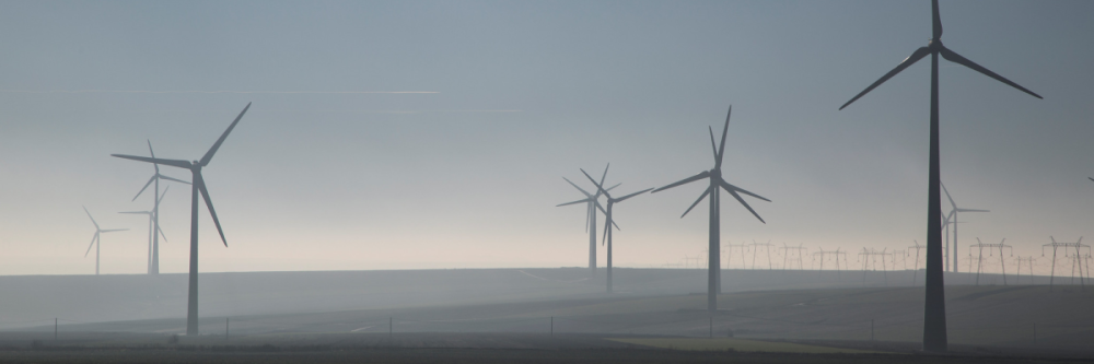 Landscape with wind turbines and electricity pylons in the distance.