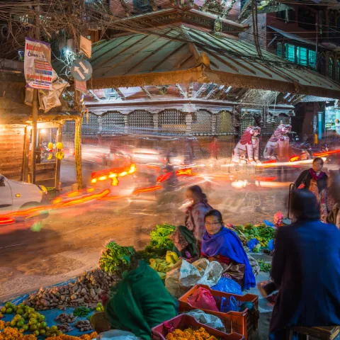Busy street with blurred traffic in the background and market place in foreground.