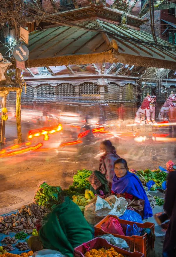 Busy street with blurred traffic in the background and market place in foreground.